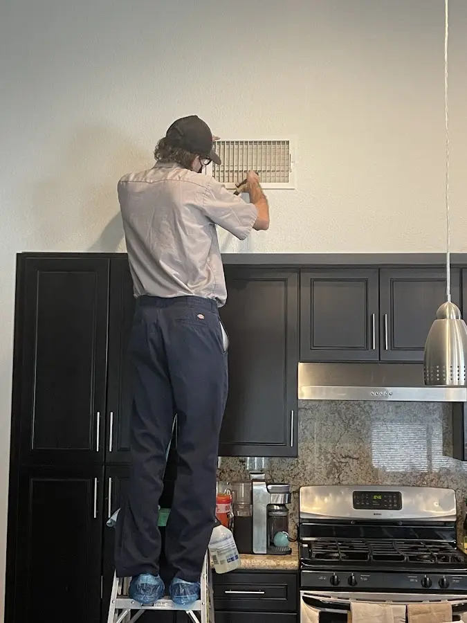 Technician inspecting an air vent during HVAC service in Twin Lakes